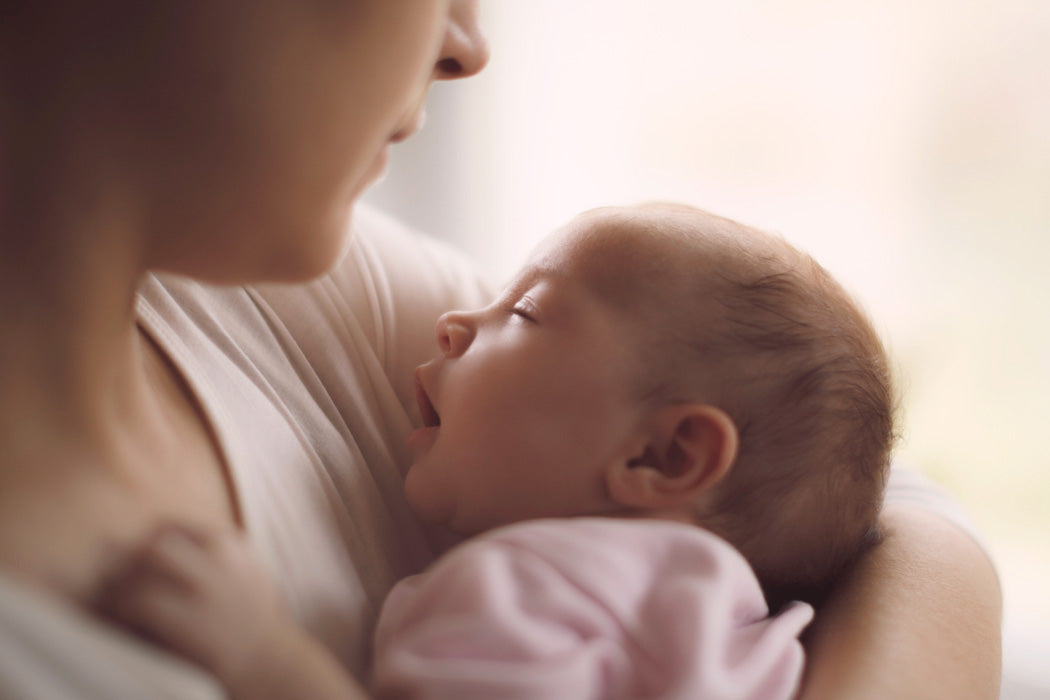 Eine Mama hält ihr neugeborenes Baby im Arm